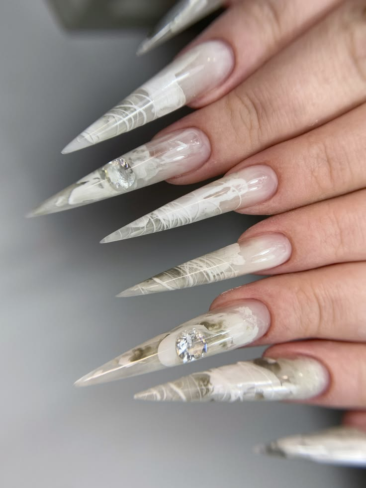 Clear marble stiletto nails with delicate thread art and crystal gemstones